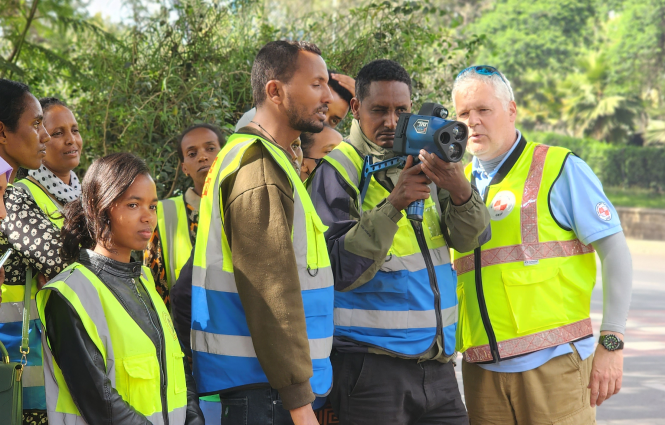 A group of road safety personnel using a speed radar.